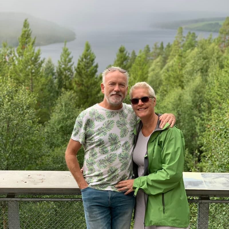 A photo of Mitzy and Steve - your hosts - standing in front of a Fjord in Norway.
